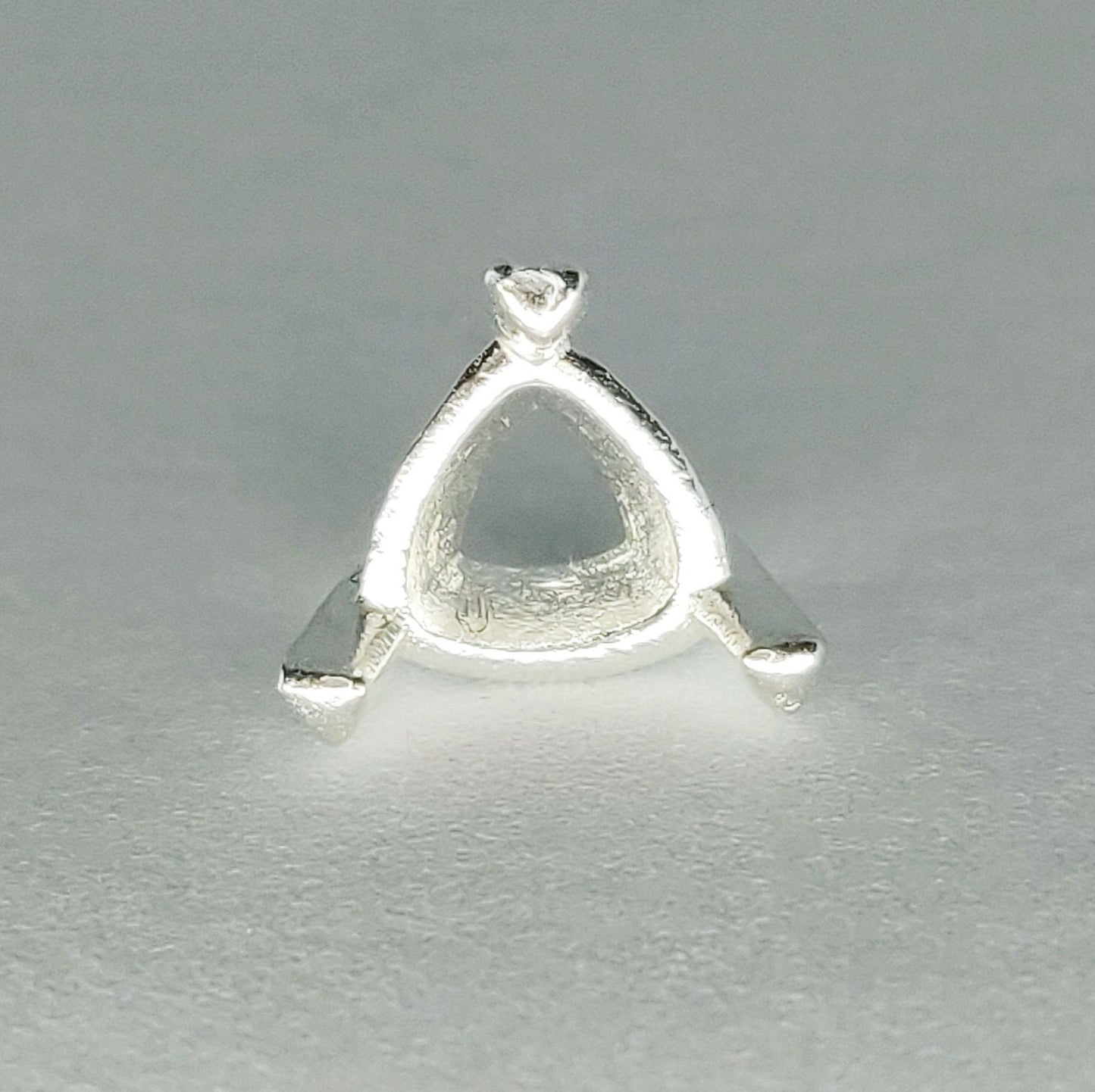 Top view of a silver trillion prong setting on a white background.